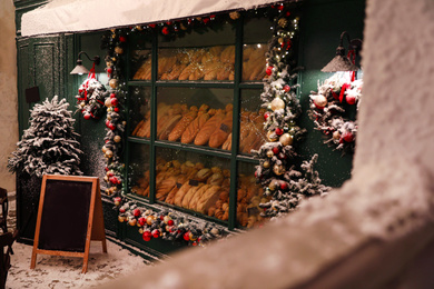 Photo of Bakery shop decorated with Christmas garland outdoors