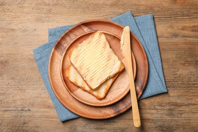 Photo of Tasty toasts with butter served on wooden table, flat lay