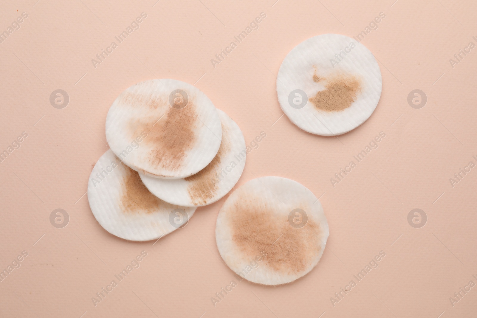 Photo of Dirty cotton pads after removing makeup on beige background, flat lay