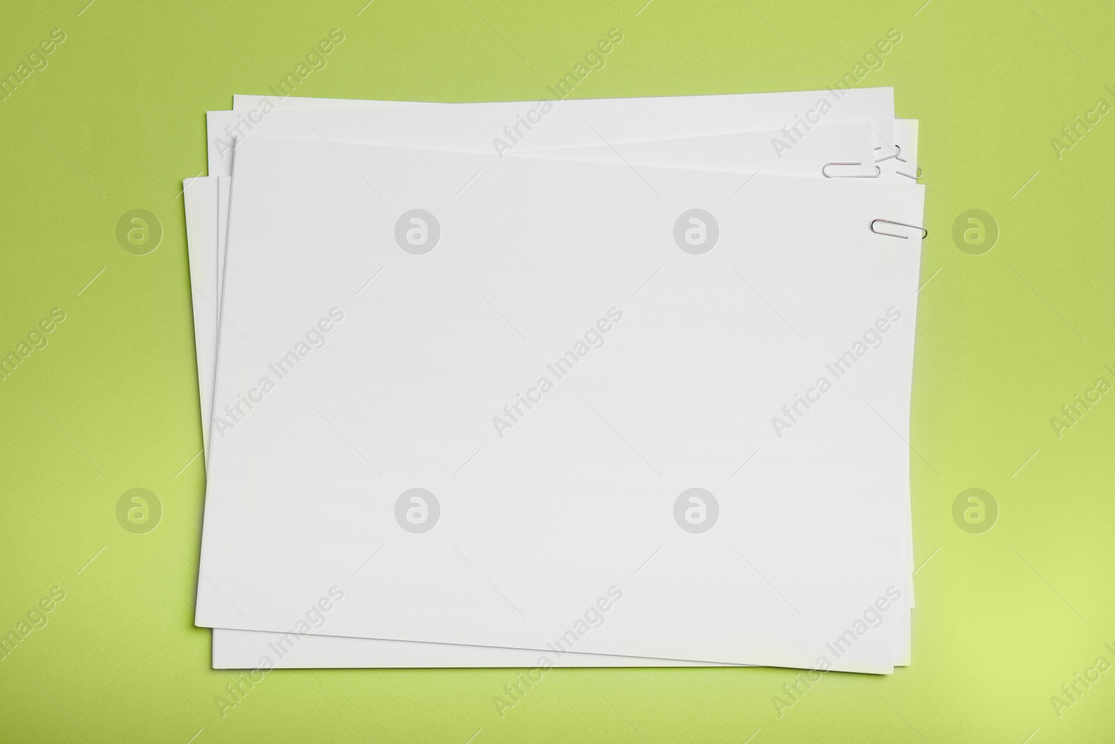 Photo of Sheets of paper with clips on light green background, top view