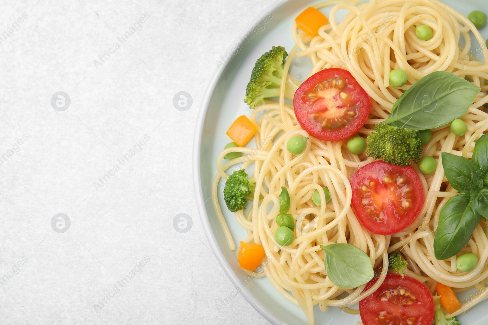 Photo of Plate of delicious pasta primavera on light gray table, top view. Space for text