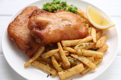 Photo of Tasty fish, chips, peas and lemon on white wooden table, closeup