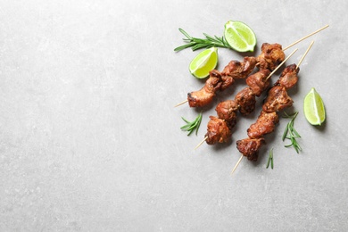 Delicious barbecued meat with rosemary and lime on grey background, top view. Space for text