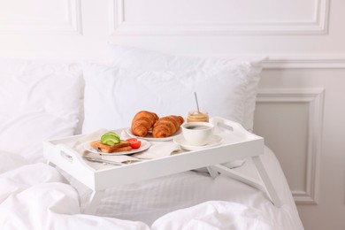 Photo of Good morning. Tray with tasty breakfast on bed at home