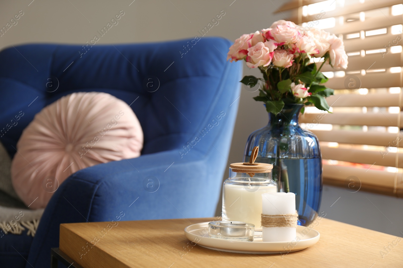 Photo of Vase with beautiful flowers and candles on wooden table indoors, copy space text. Interior elements