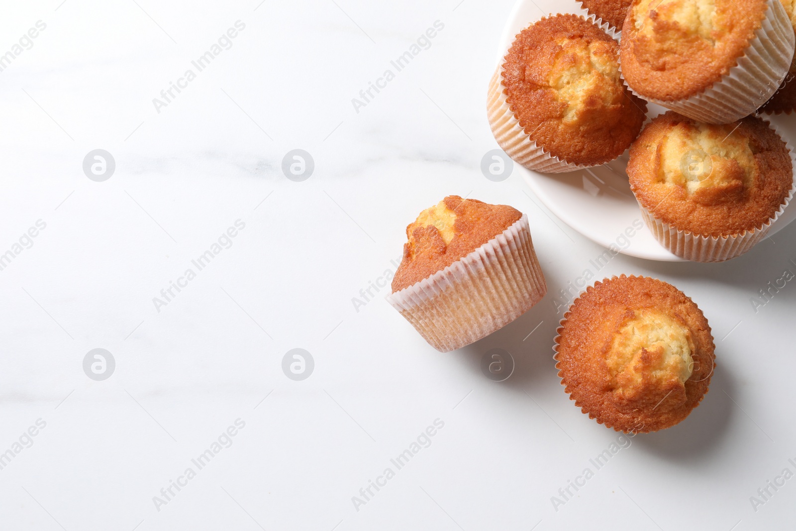 Photo of Delicious sweet muffins on white marble table, flat lay, Space for text