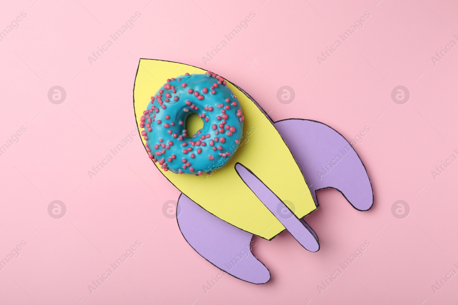 Photo of Rocket made with donut and paper on pink background, top view