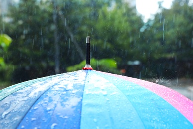 Photo of Colorful umbrella outdoors on rainy day, closeup