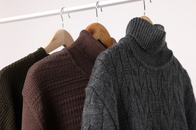 Photo of Rack with different casual sweaters on light background, closeup