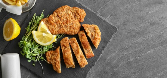 Image of Tasty schnitzels served on grey table, top view. Banner design