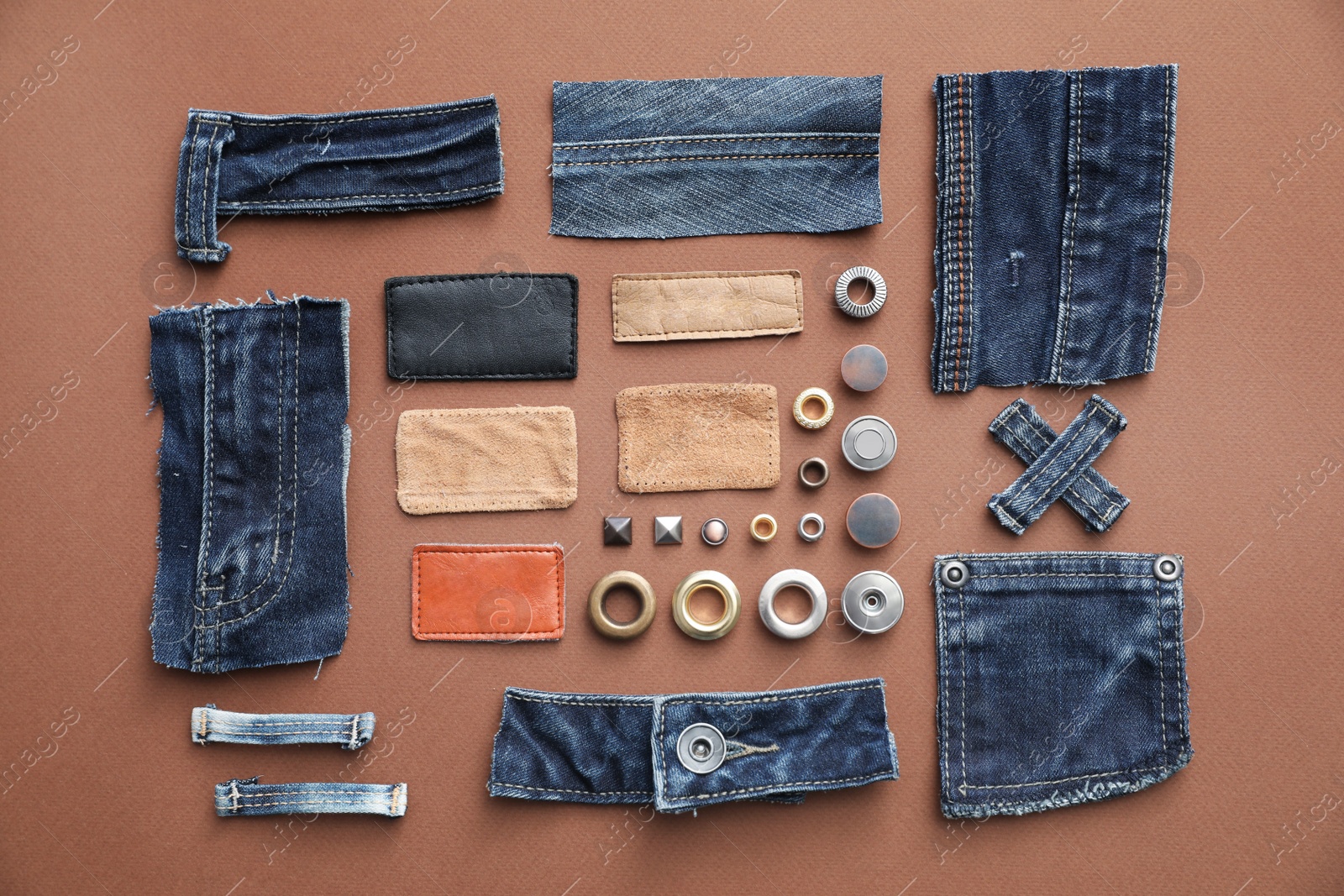 Photo of Flat lay composition with garment accessories and cutting details for jeans on brown background