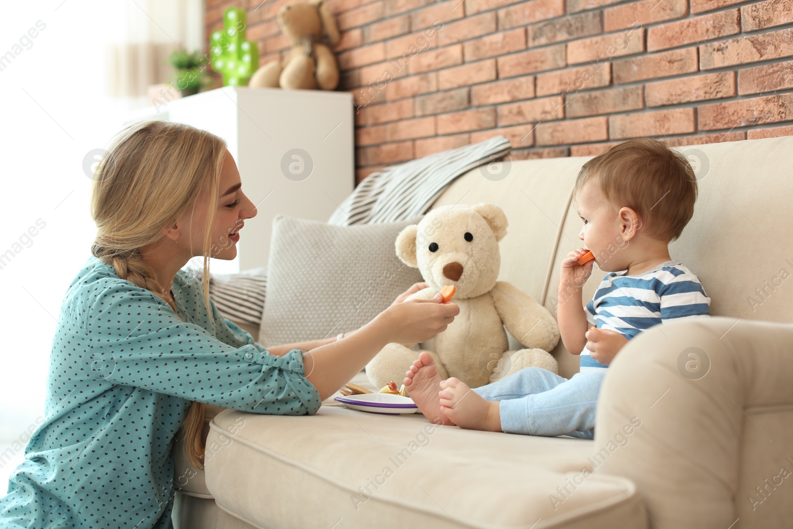 Photo of Woman playing with child while feeding him at home. Healthy baby food