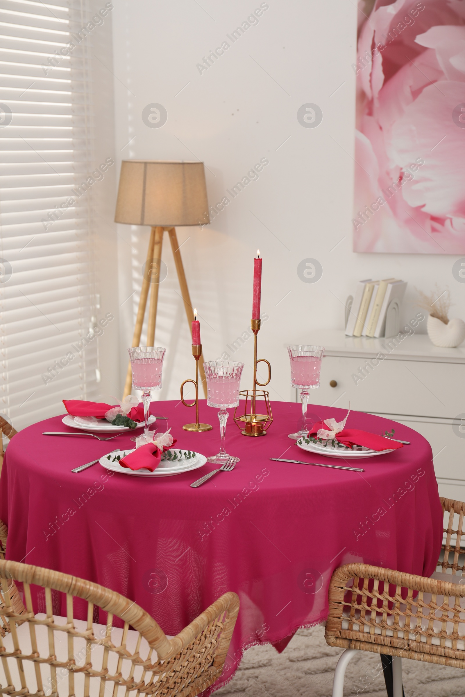 Photo of Beautiful table setting with green branches and burning candles in dining room