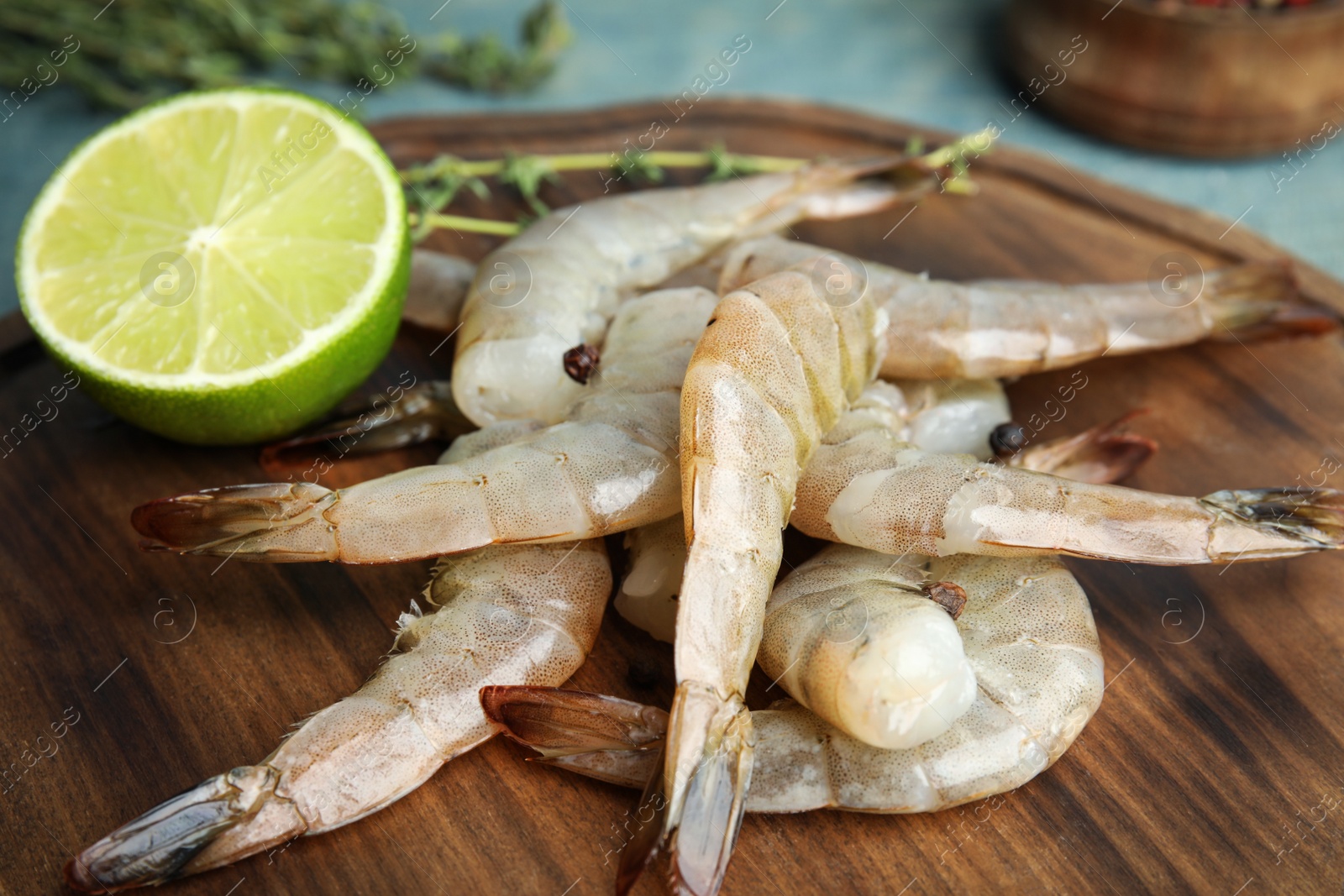 Photo of Fresh raw shrimps and lime on wooden board, closeup