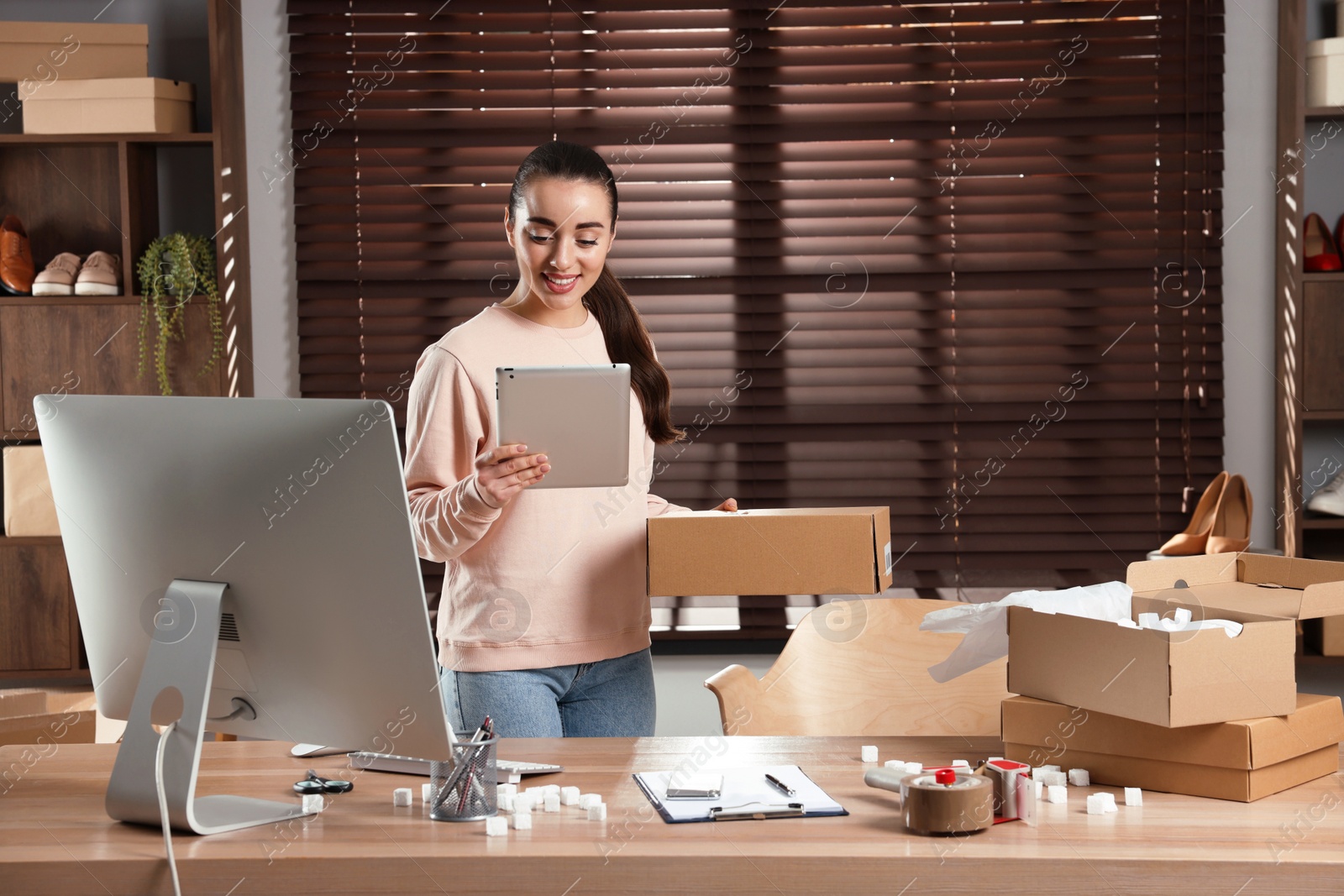 Photo of Seller with tablet and parcel in office. Online store