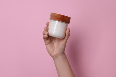 Woman holding jar of cosmetic product on pink background, closeup