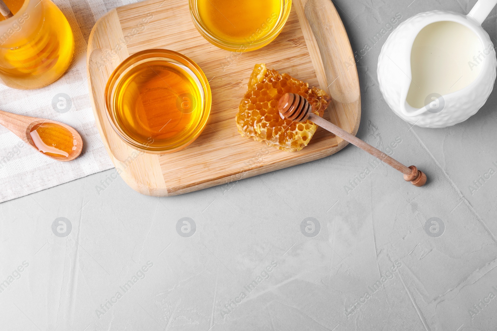 Photo of Flat lay composition with tasty honey on light grey table, space for text