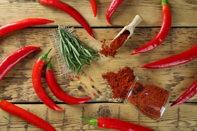 Photo of Scoop and glass jar of ground red pepper with ingredients on wooden table, flat lay