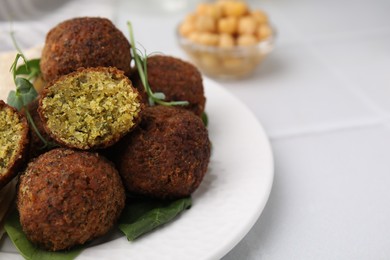 Photo of Delicious falafel balls and herbs on white table, closeup. Space for text