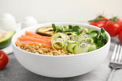 Delicious lentil bowl with salmon, avocado and cucumber on grey table