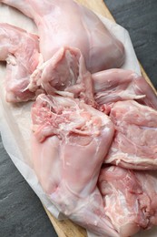 Photo of Fresh raw rabbit legs on black table, top view