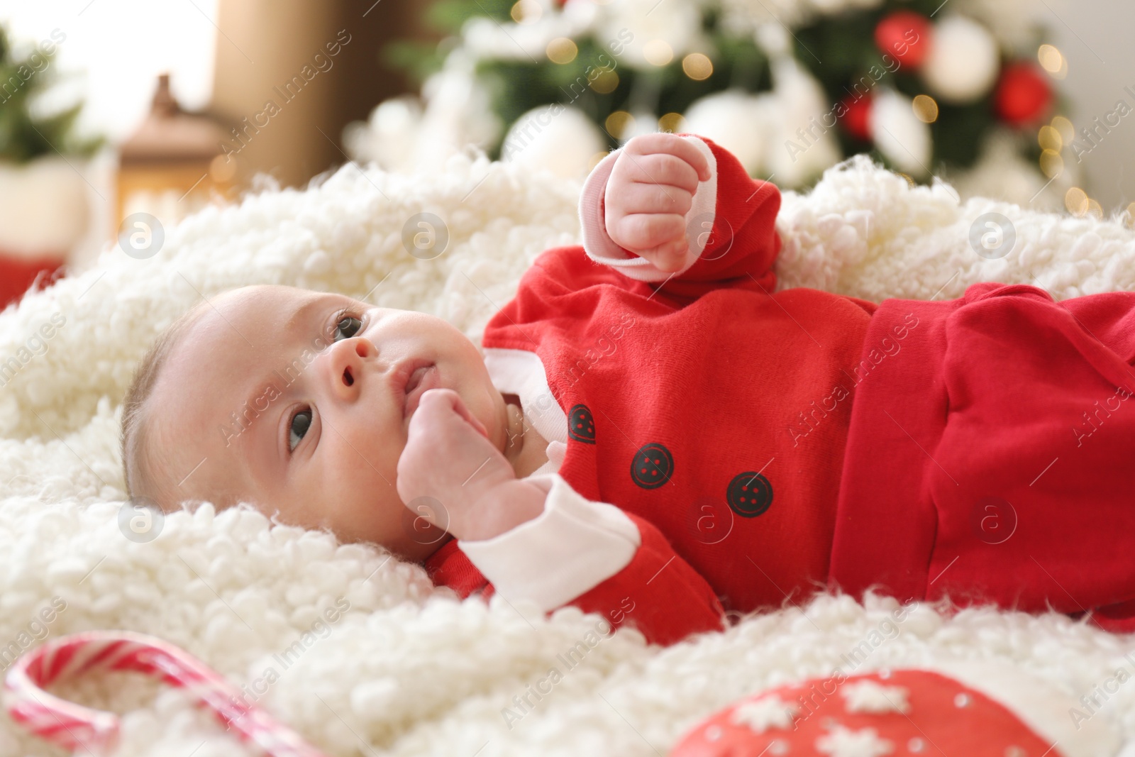 Photo of Cute little baby on soft blanket in room decorated for Christmas