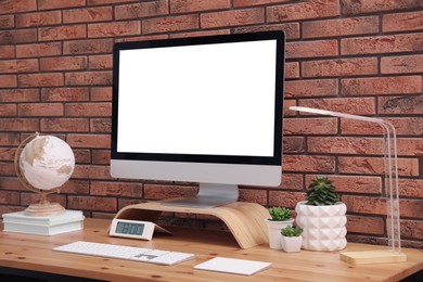 Photo of Stylish workplace with modern computer near brick wall indoors. Space for text