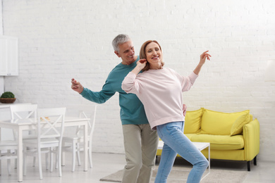 Photo of Happy senior couple dancing together in kitchen