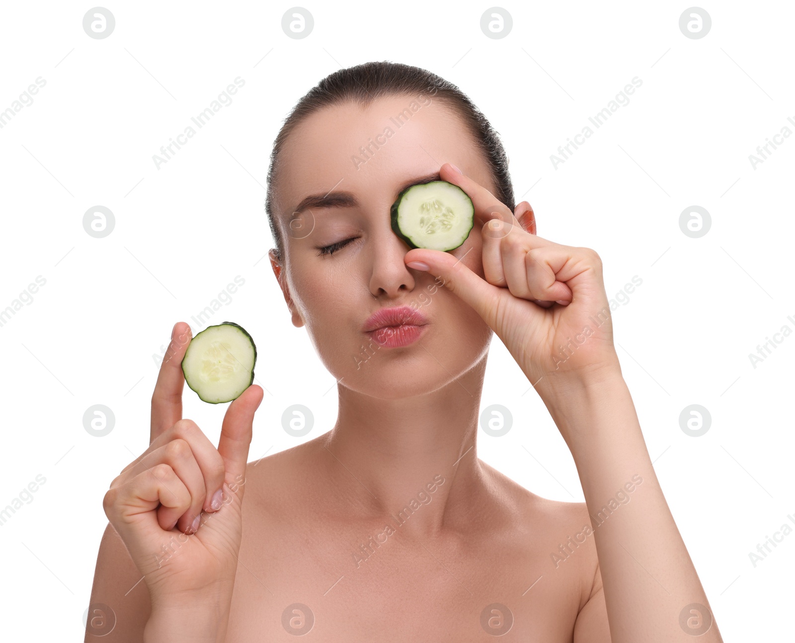 Photo of Beautiful woman covering eye with piece of cucumber and blowing kiss on white background