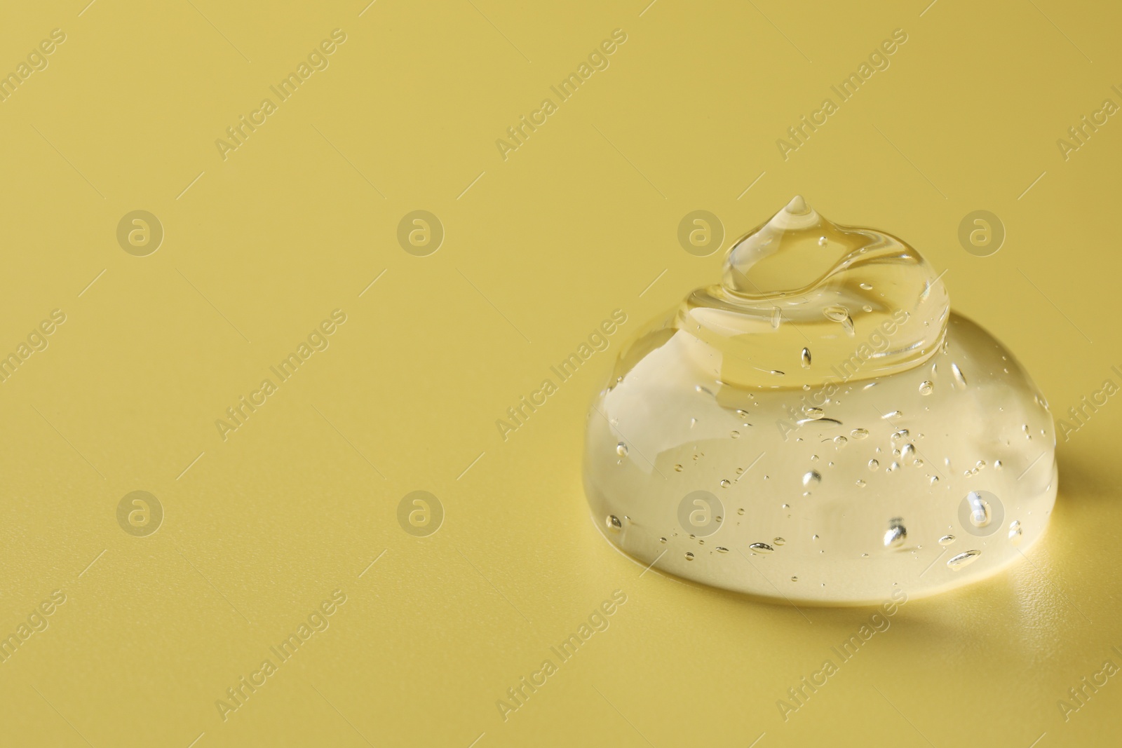 Photo of Sample of clear cosmetic gel on yellow background, closeup. Space for text