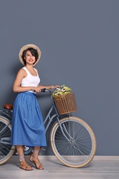 Portrait of beautiful young woman with bicycle near color wall