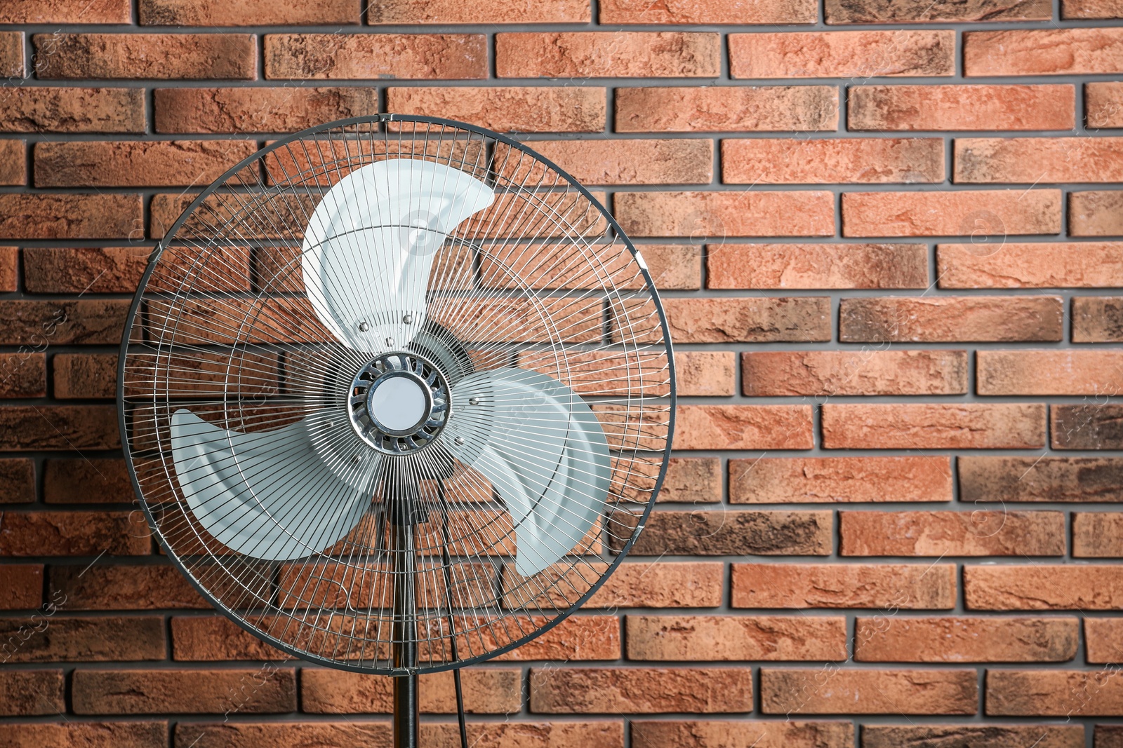 Photo of Electric fan near brick wall, space for text. Summer heat