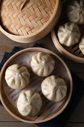 Delicious bao buns (baozi) on wooden table, flat lay