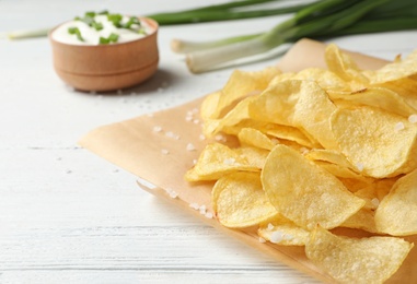 Delicious crispy potato chips on table, space for text