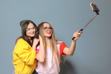 Photo of Attractive young women taking selfie on grey background