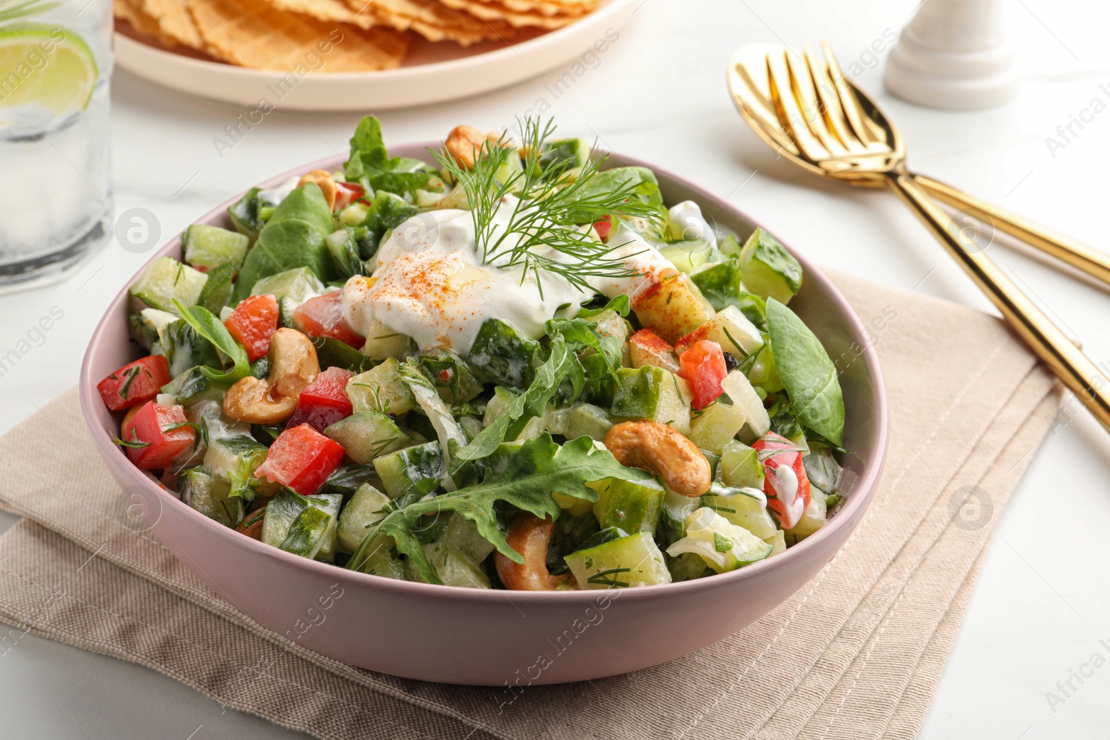 Photo of Bowl of delicious cucumber salad served on white table, closeup