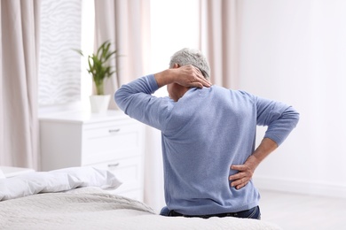 Senior man suffering from back pain at home