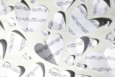 Photo of Paper hearts with music notes on white wooden background, flat lay