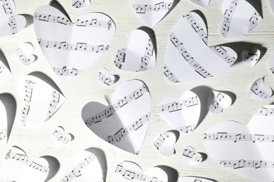 Paper hearts with music notes on white wooden background, flat lay