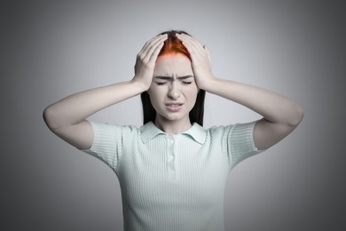 Young woman having headache on light grey background