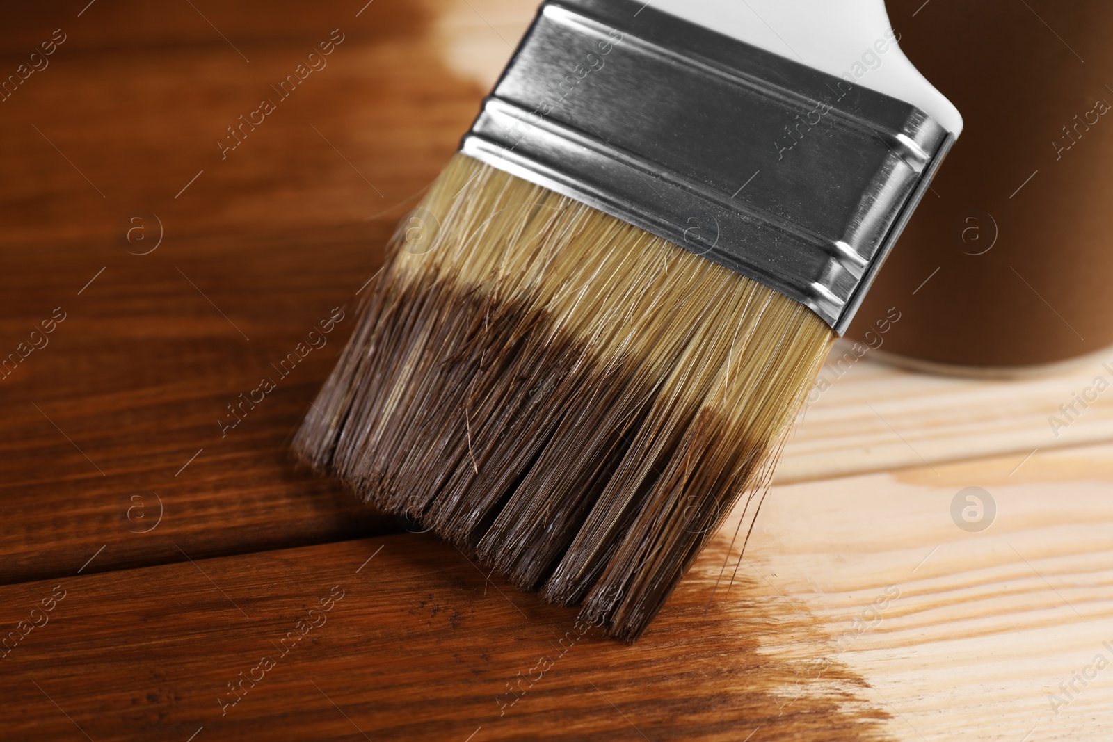 Photo of Applying wood stain with brush onto wooden surface, closeup