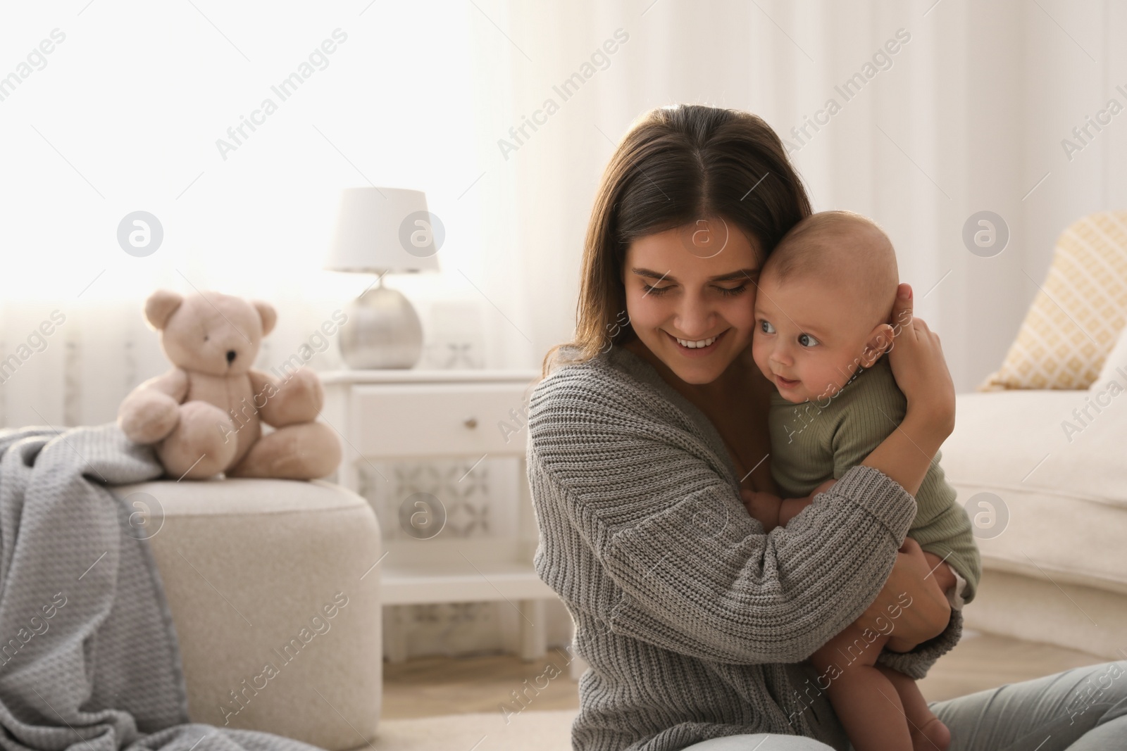 Photo of Young woman with her little baby on floor at home