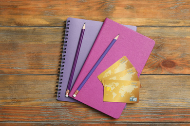 Photo of Notebooks, pencils and credit cards on wooden background, top view