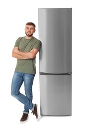 Young man near closed refrigerator on white background