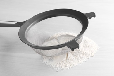 Photo of Sieve and flour on white wooden table