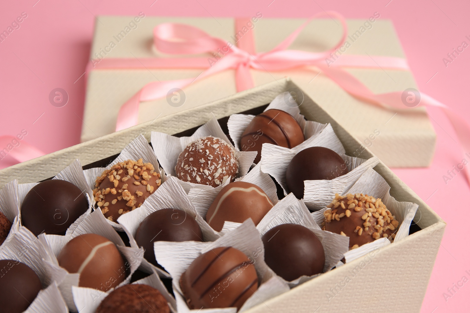 Photo of Box of delicious chocolate candies on pink background, closeup