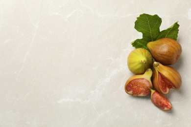 Tasty raw figs and green leaf on light grey marble table, flat lay. Space for text