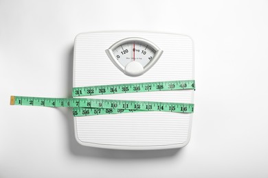 Weight loss concept. Scales and measuring tape on white background, top view