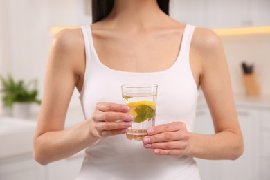 Photo of Young woman with glass of fresh lemonade at home, closeup