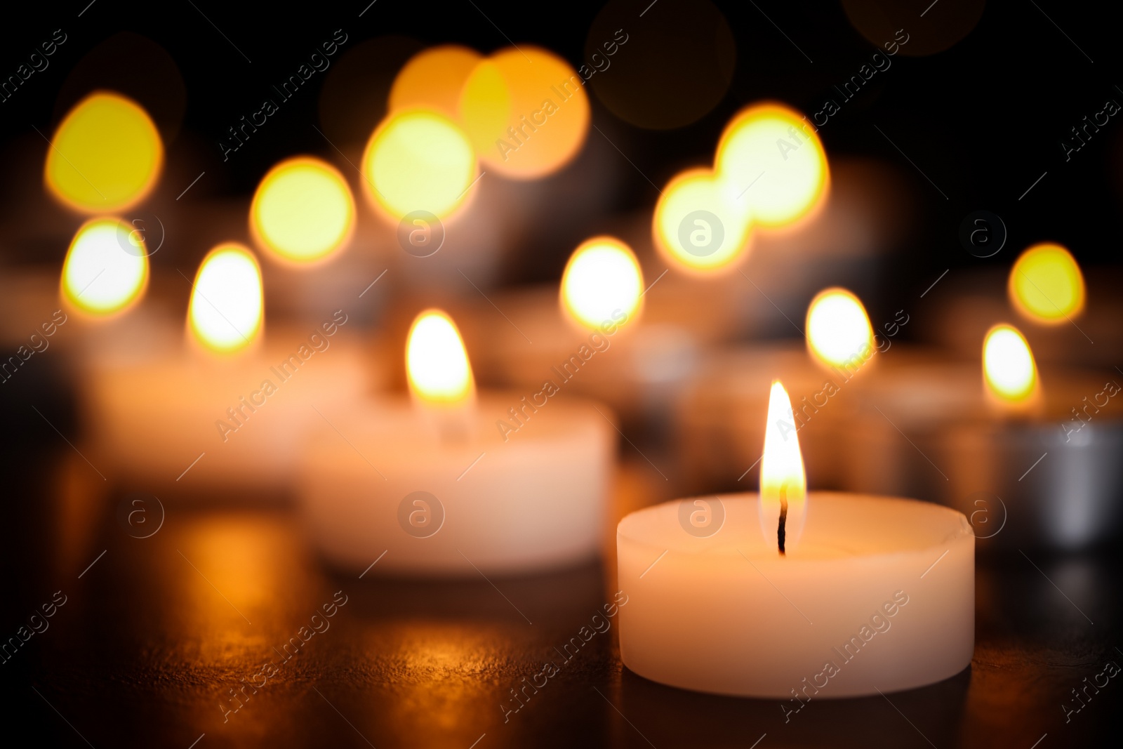 Photo of Burning candles on table, closeup. Funeral symbol